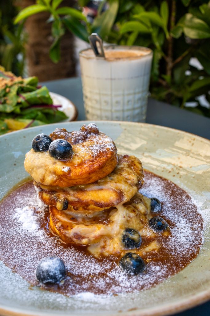 Pancakes auf einem Teller und Chai Latte im Ramasuri in Wien.