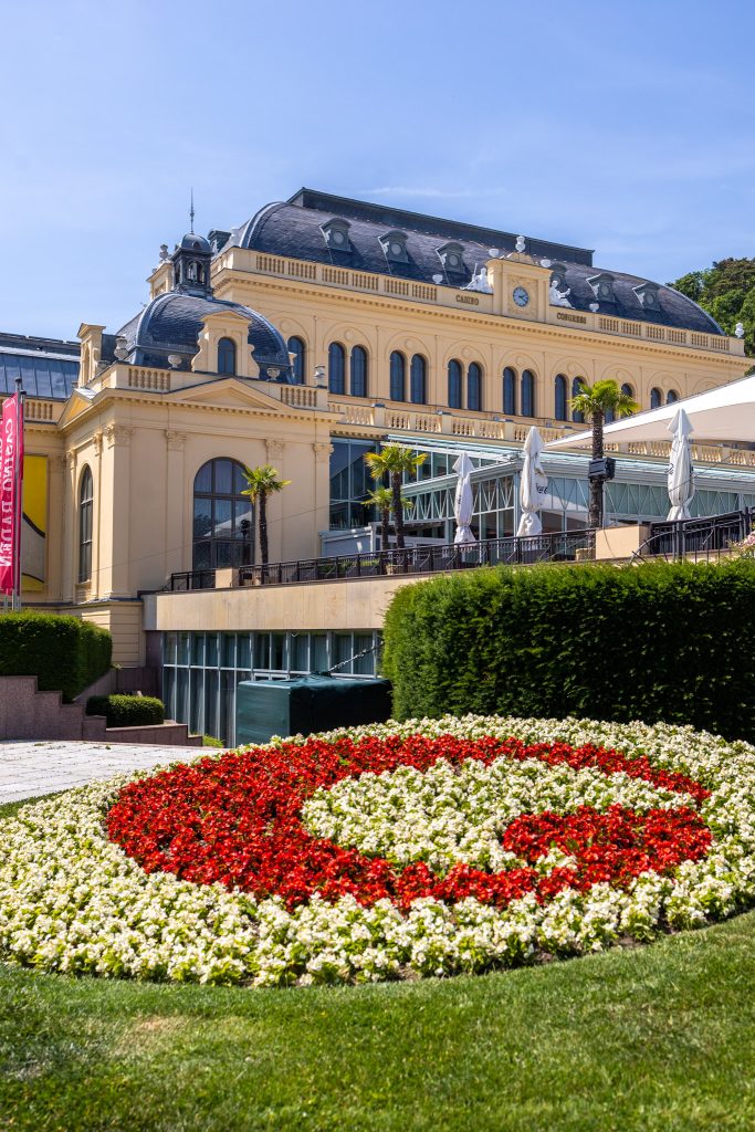 Casino in Baden bei Wein mit roten und weißen Blumen im Vordergrund, die ein C formen.